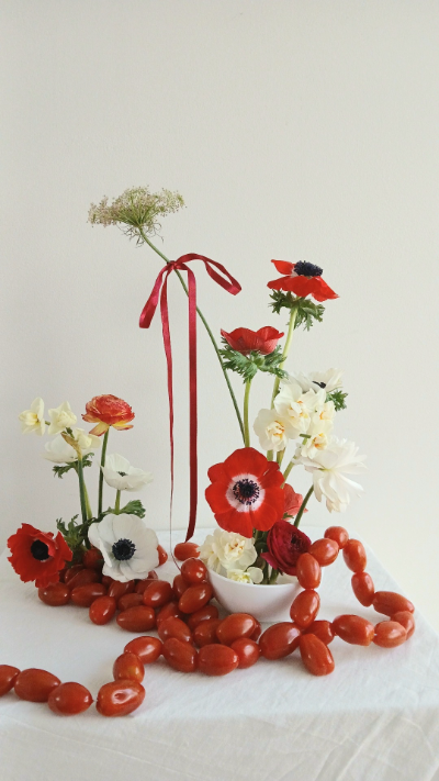 bouquet de fleurs posé sur une table avec des coquelicots rouges et blancs ainsi que des tomates