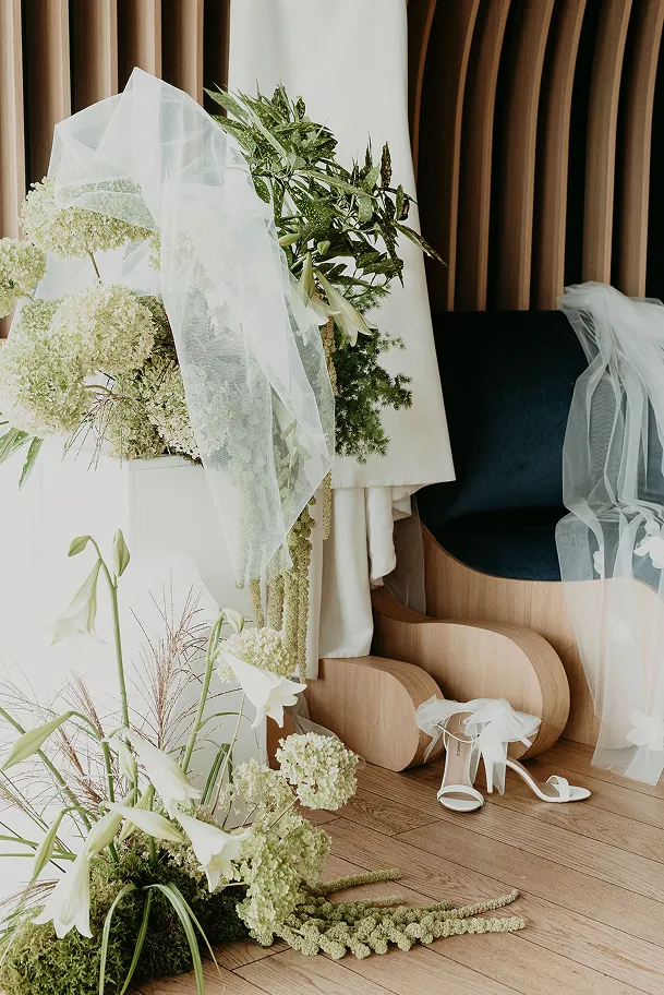 dans un décor contemporain se trouvent diverses fleurs blanches et des nappes blanches