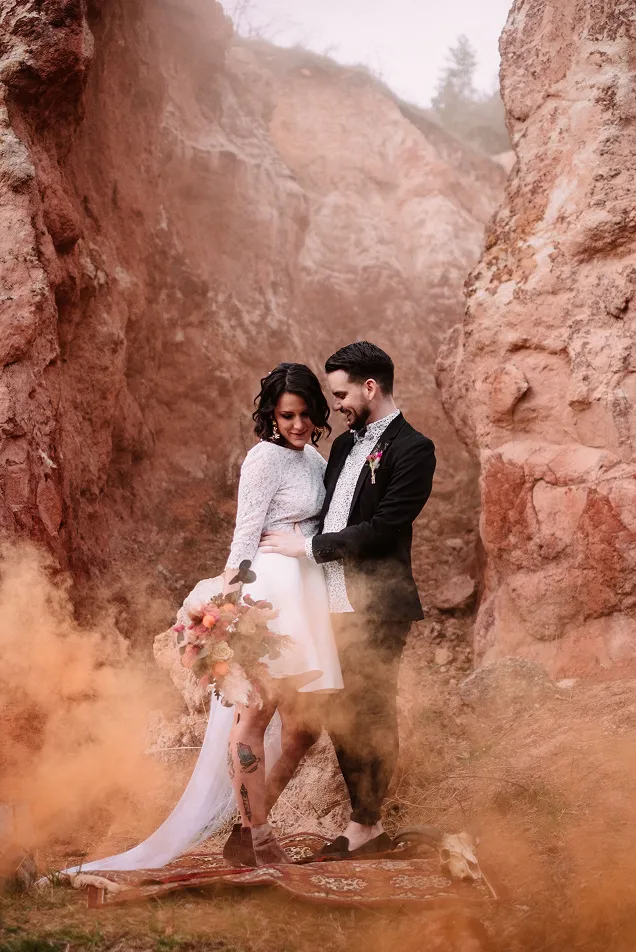 dans un décor argile, pose pour une photo un couple de mariés