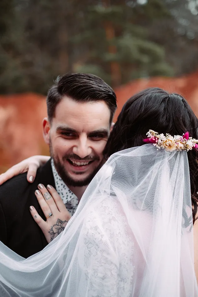 un couple de mariés souriant se tenant dans leurs bras avec l’homme de face et la femme de dos