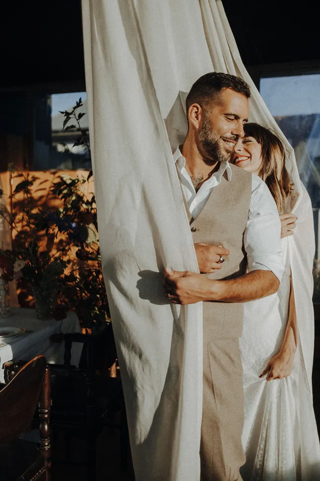 enlacé dans un voile blanc se trouve un couple de mariés souriant et de face