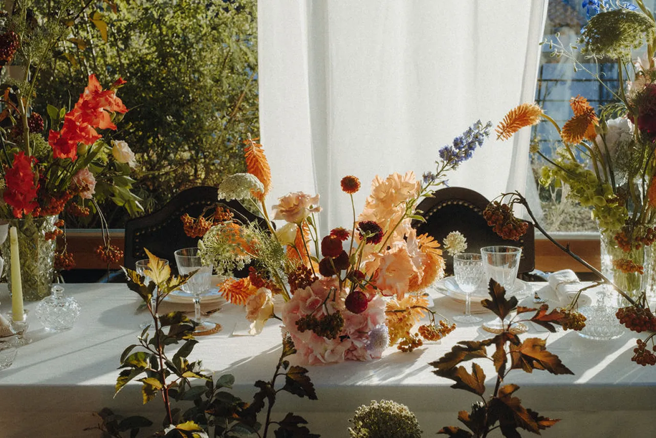 sur une table blanche se trouvent de multiples fleurs aux diverses couleurs