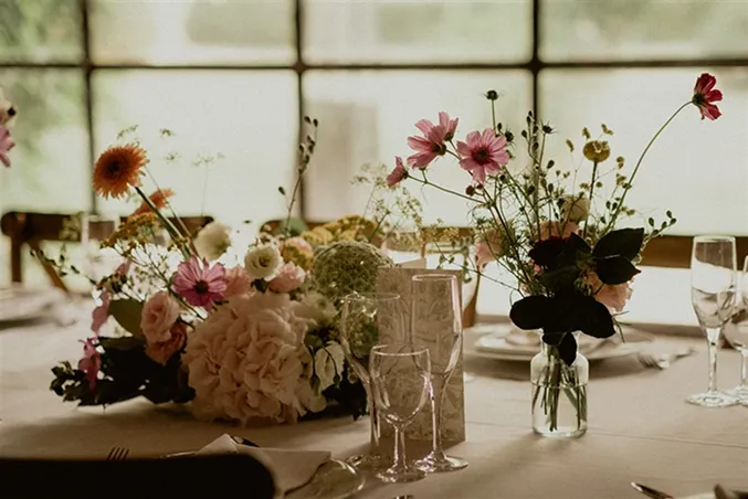 une table lors d’un mariage avec des fleurs des couleurs blanc, rose et orange