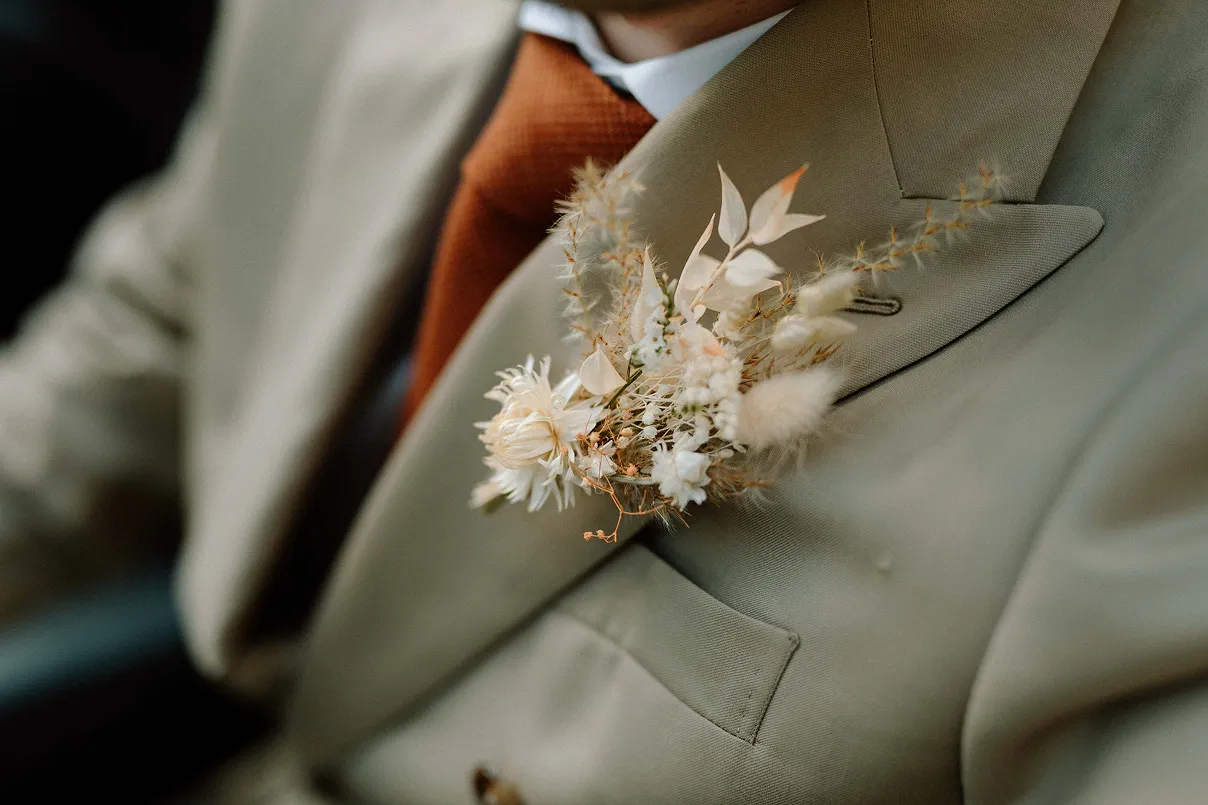 une fleur accrochée sur le col d’un costume de marié