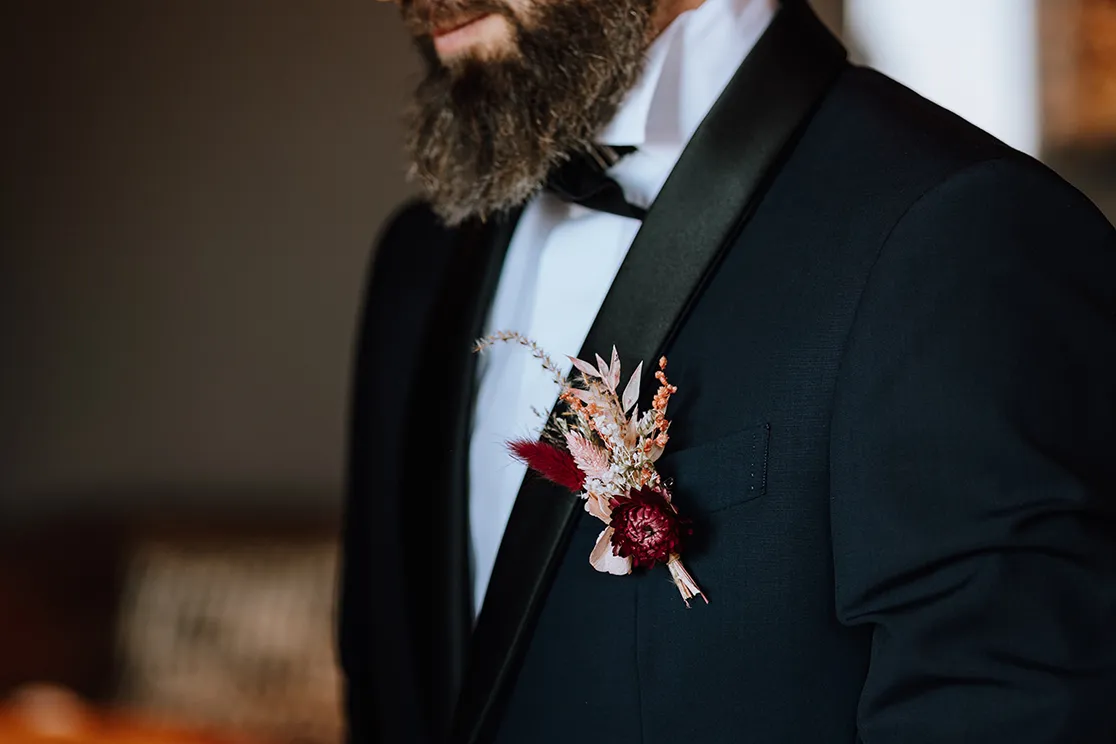 un petit bouquet de fleurs accroché au col d’un costume d’homme