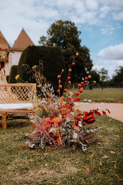 dans un jardin se trouve une composition florale composée des couleurs rouge, orange, blanc et jaune ainsi que du rose et des feuilles vertes