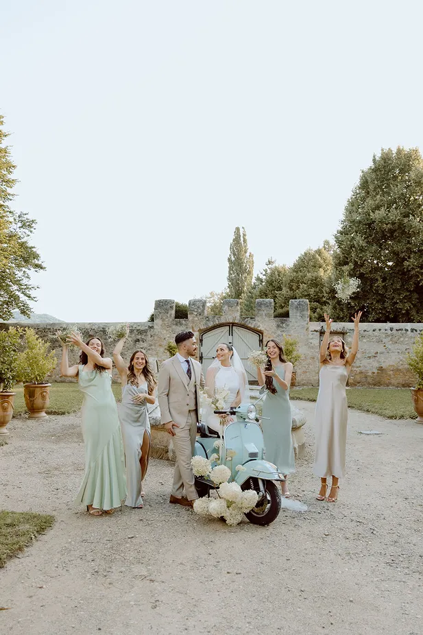 une photo d’un couple de mariés entouré d’amis avec un scooter se trouvant tous dans un jardin